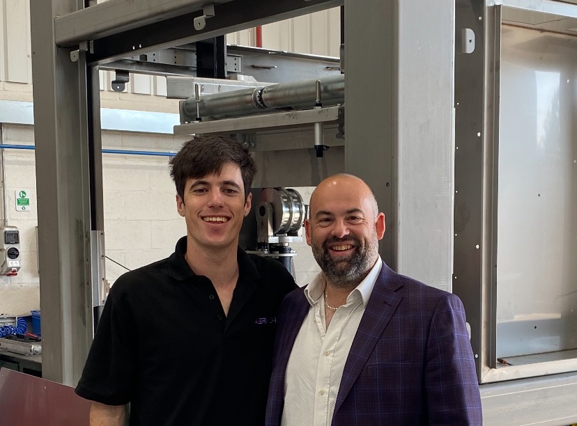 Two men in front of a palletizer